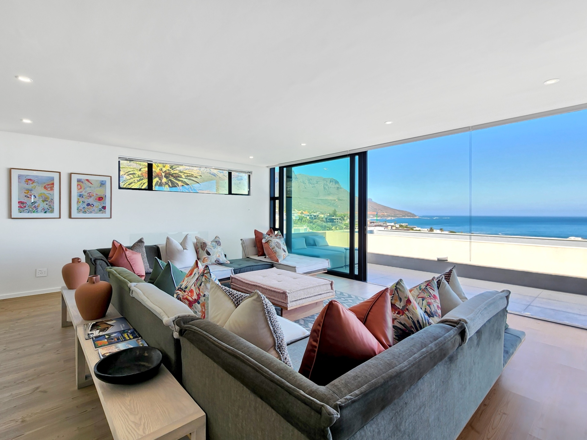 Top-floor living room with stacking doors open to panoramic Camps Bay ocean views