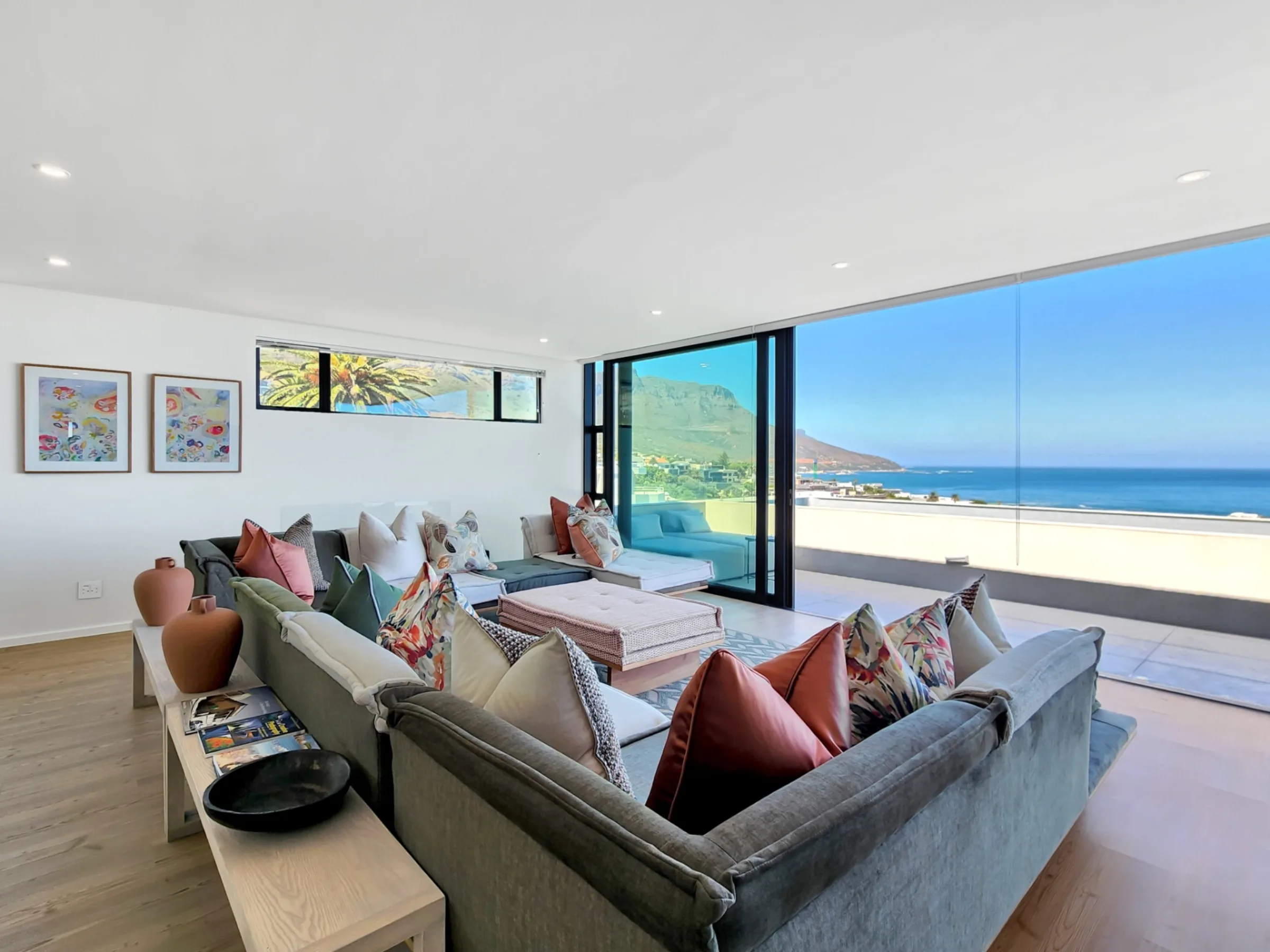 Top-floor living room with stacking doors open to panoramic Camps Bay ocean views